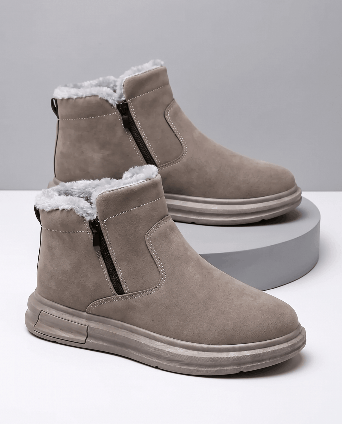 Taupe wide toe box winter boots with side zip and plush fleece lining displayed on stacked white platforms.