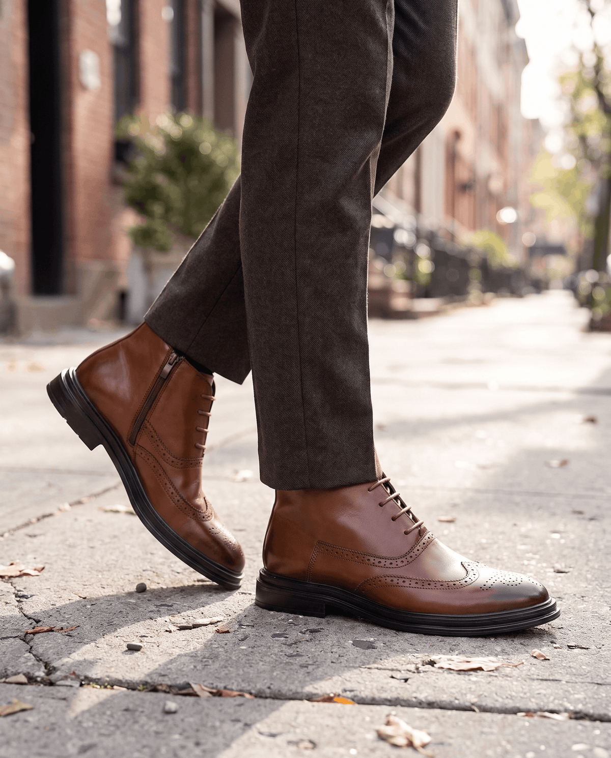 Man walking on a sunlit street in brown brogue ankle boots and dark trousers