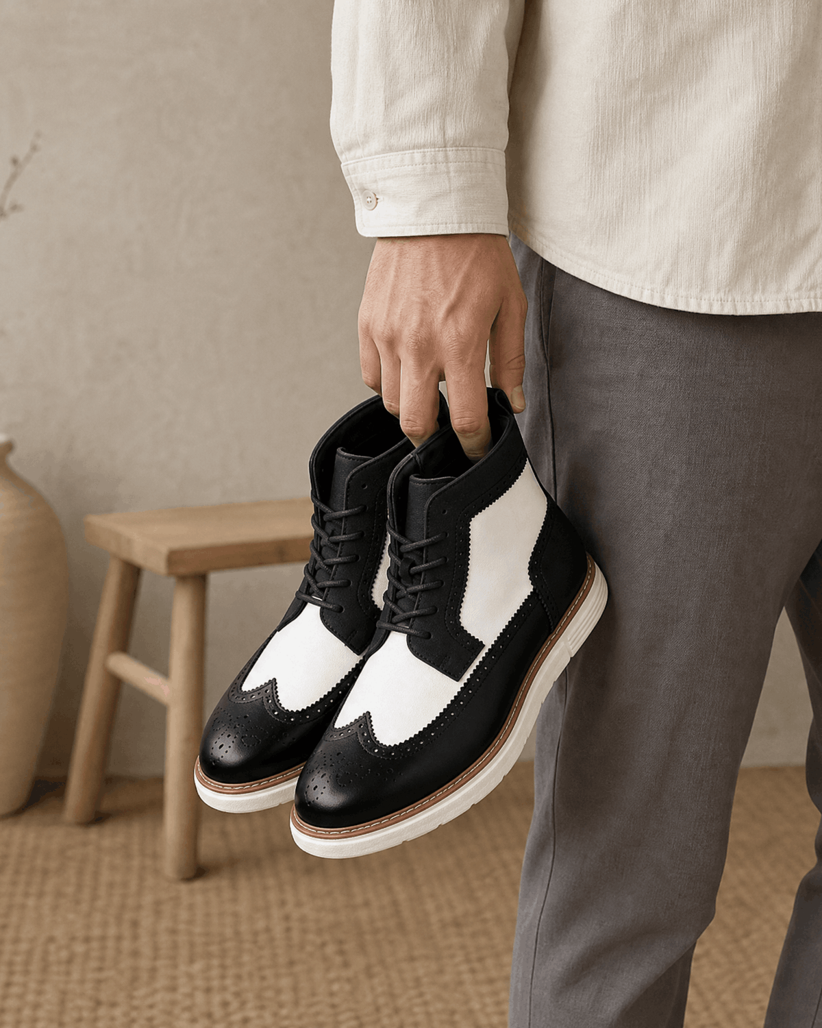 Black and white smooth grain leather wingtip boots featuring brogue perforations, a chunky white cupsole, and lace-up front.