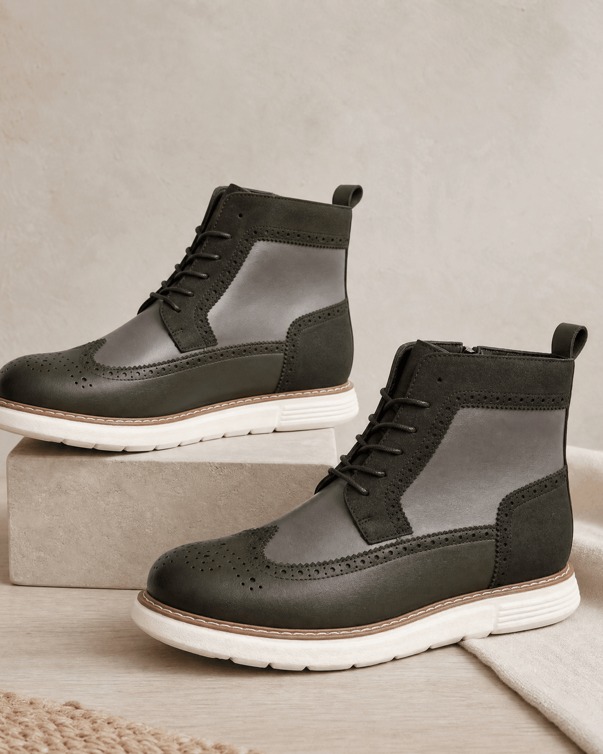Gray wingtip boots in smooth grain with matte panels, brogue perforations, side zips, and a chunky white cupsole.