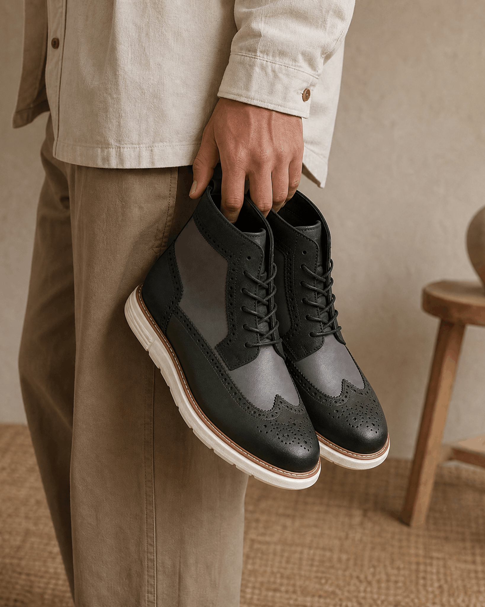 Gray smooth grain wingtip boots with brogue perforations, matte panels, and a chunky white cupsole held by hand.