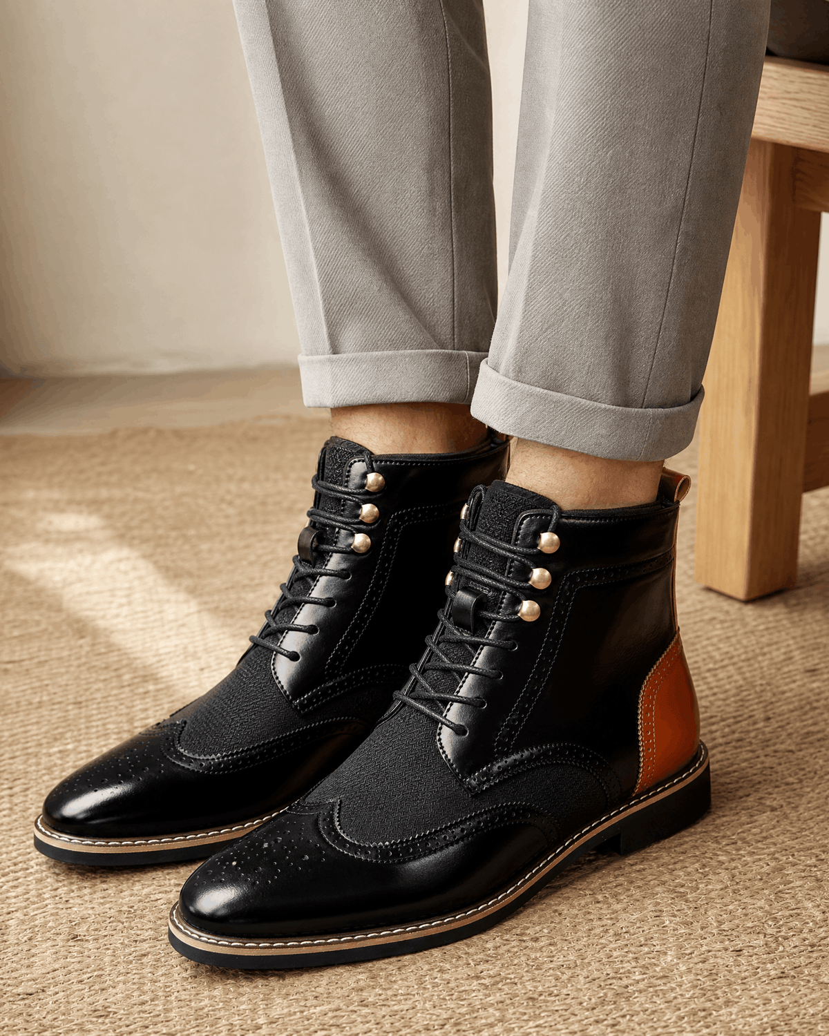 Black smooth grain leather ankle boots with wingtip brogue detailing, woven panels, metal eyelets, and a block heel.