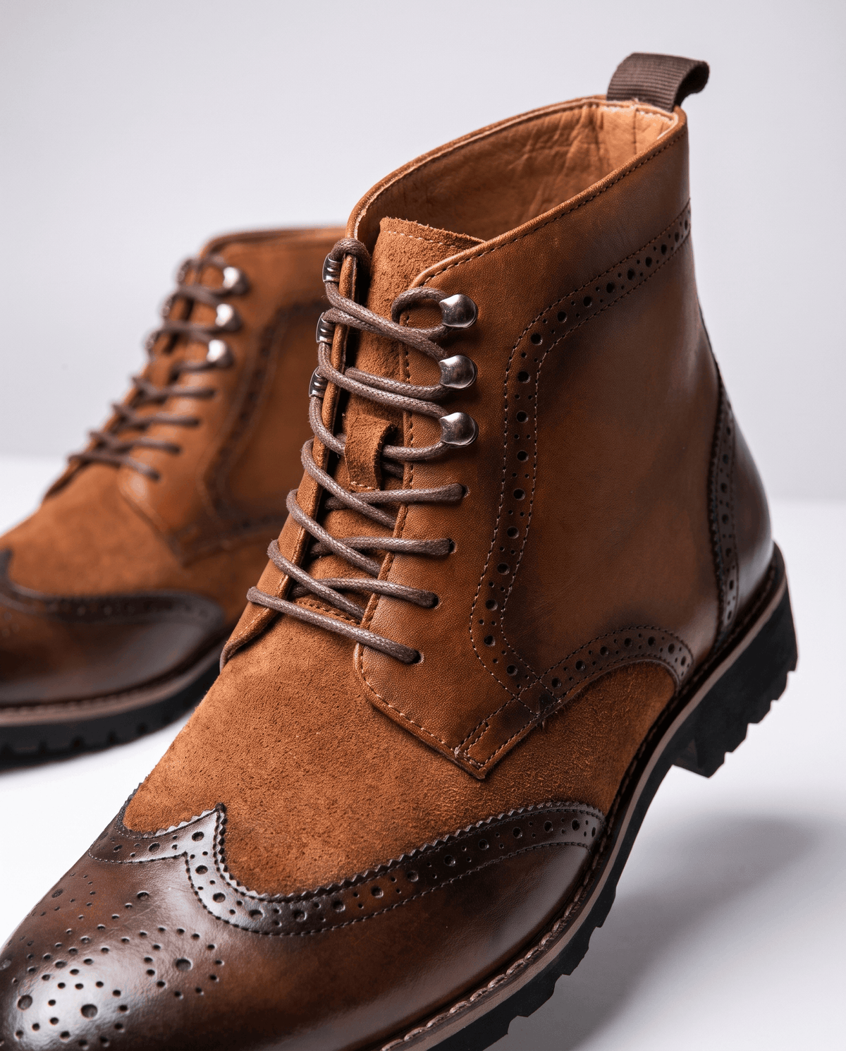 Close-up of brown suede boot with laces, brogue perforations and chunky tread sole