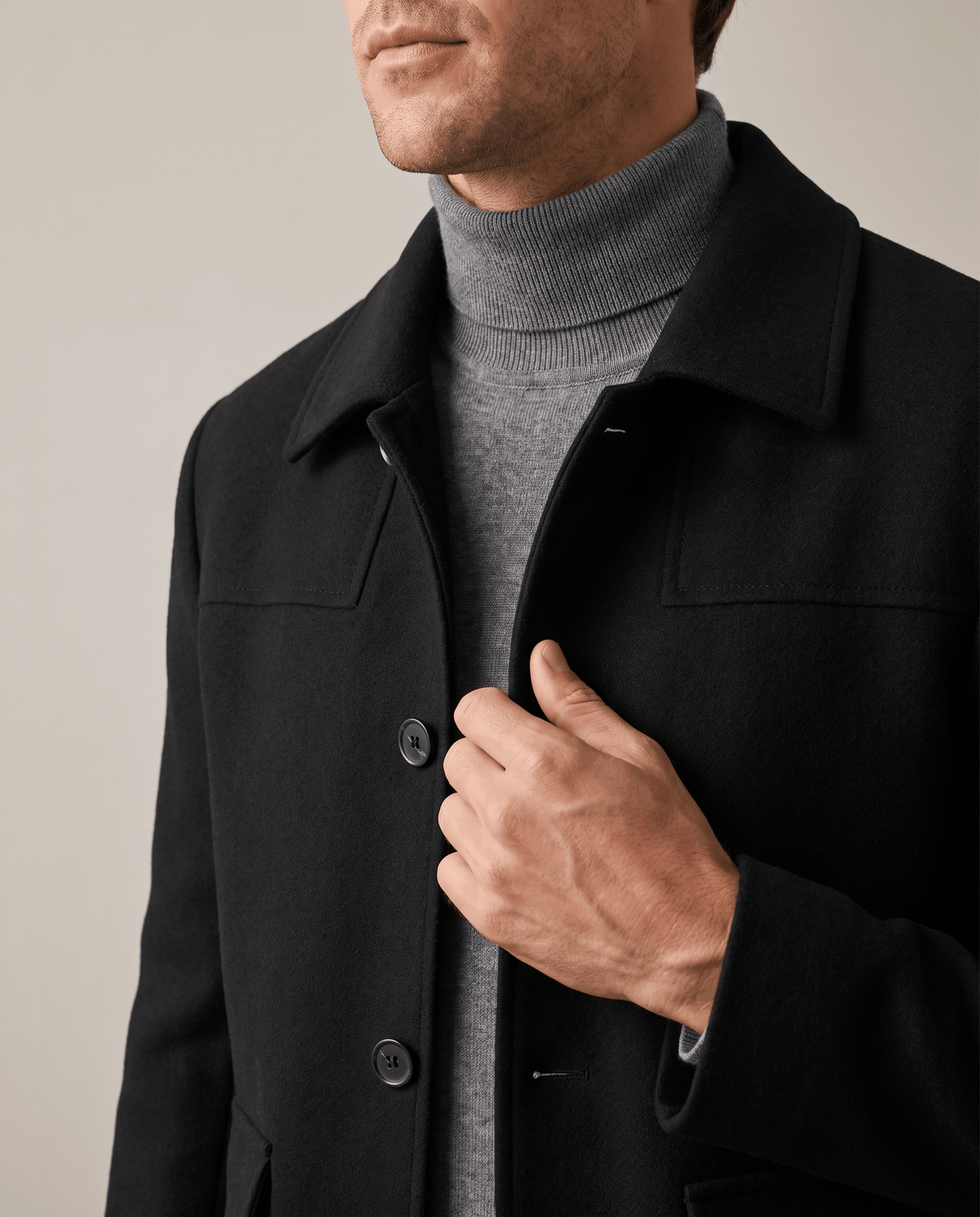 Hand fastening a button on the black coat, lapel and placket in close crop