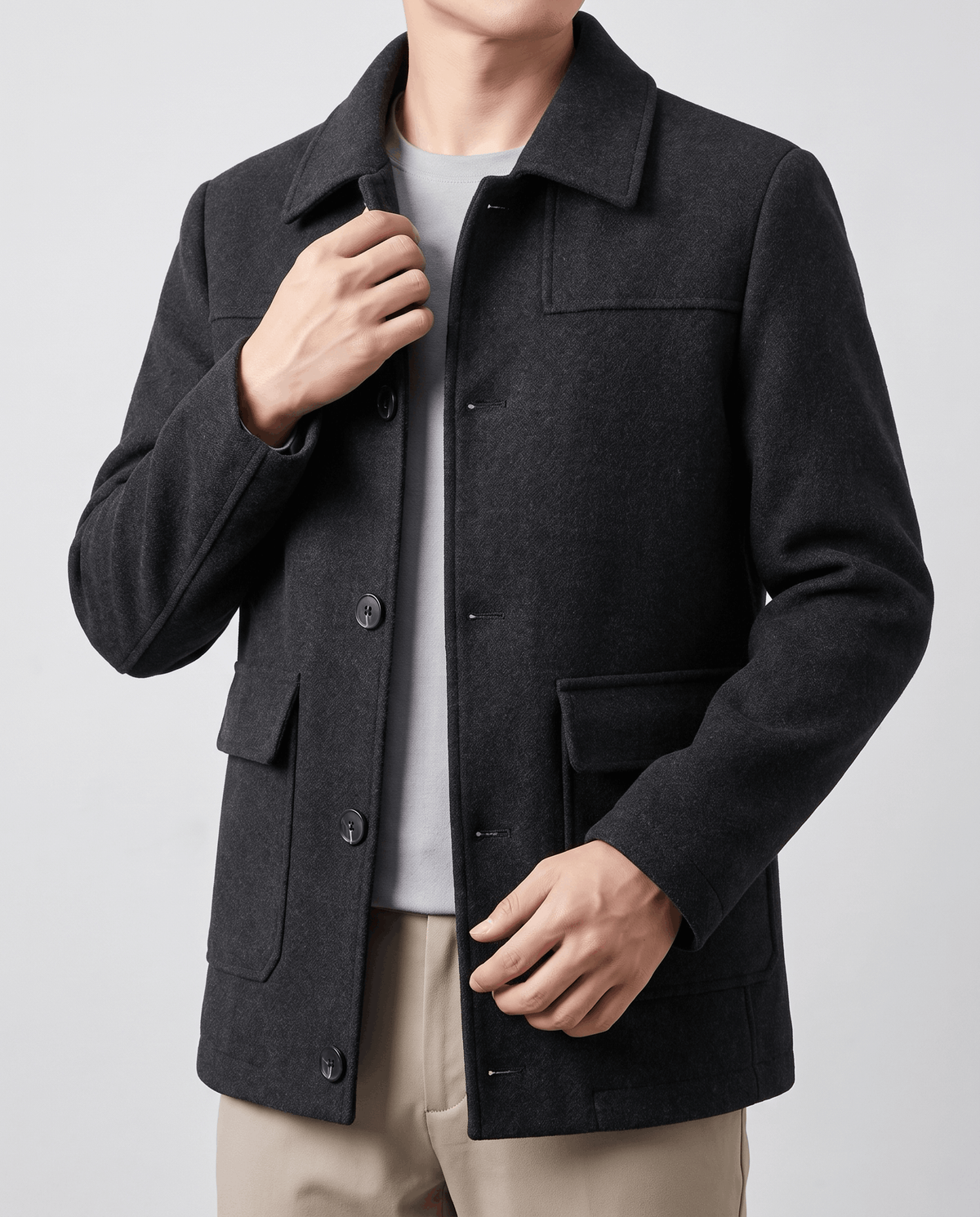 Black coat worn open over tan trousers, hands at the sides