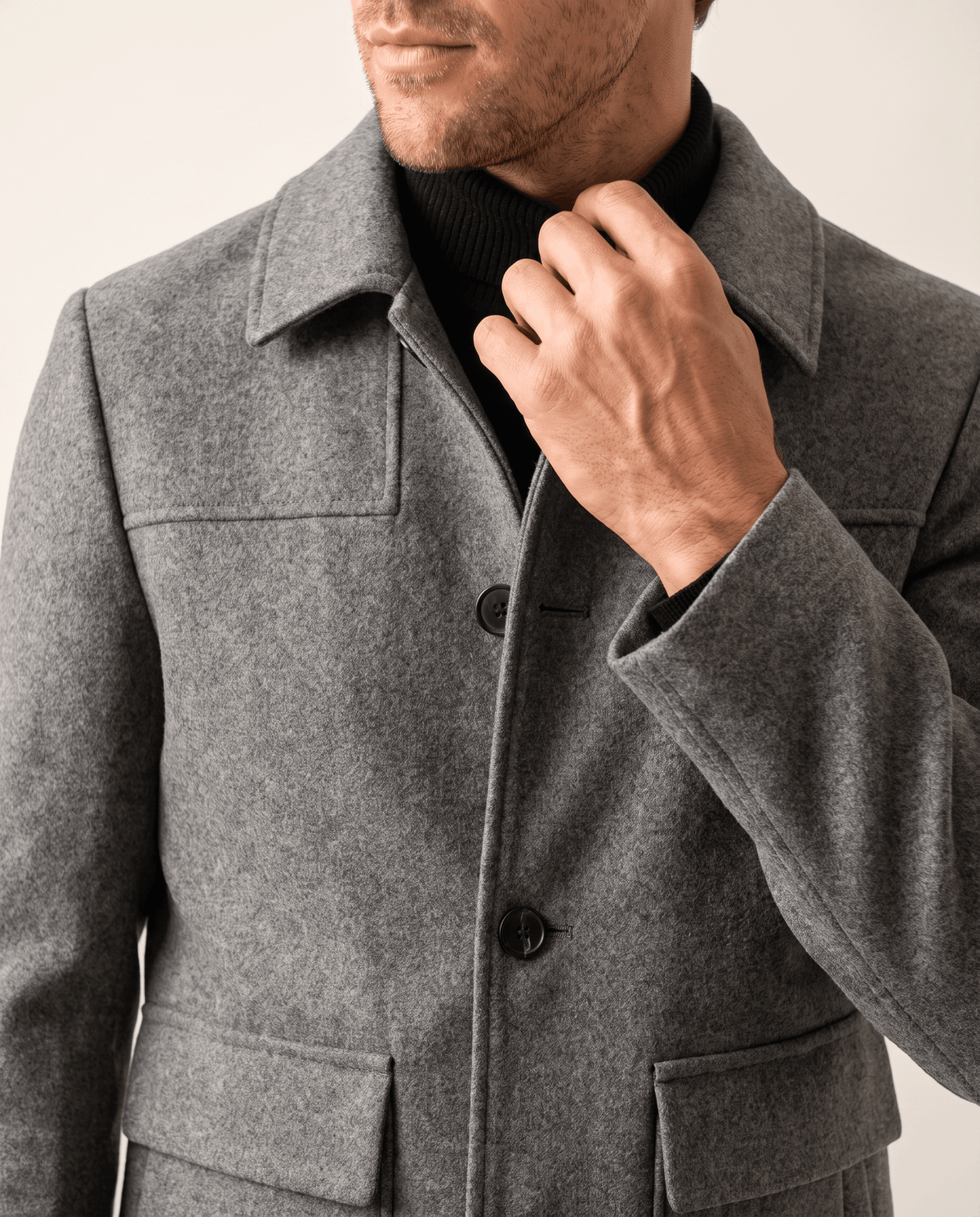 Notch lapel turned up at the neck, hand holding the collar edge