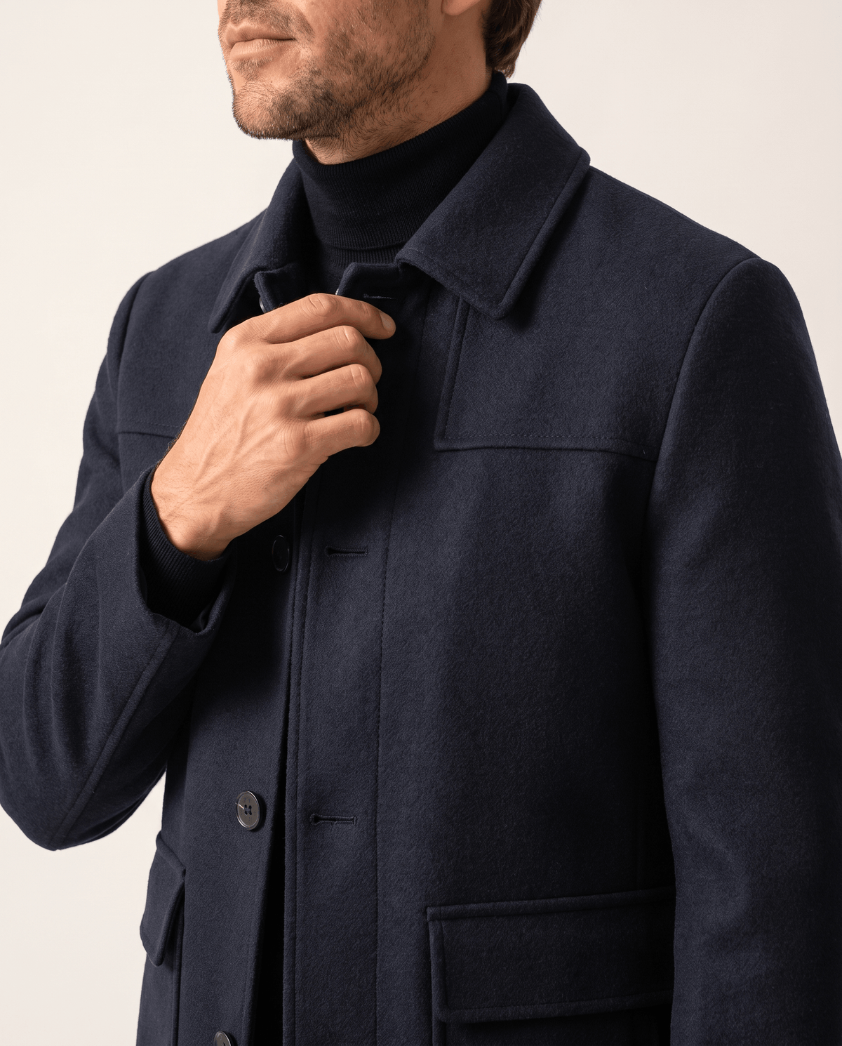 Hand adjusting the collar of the navy coat in close crop
