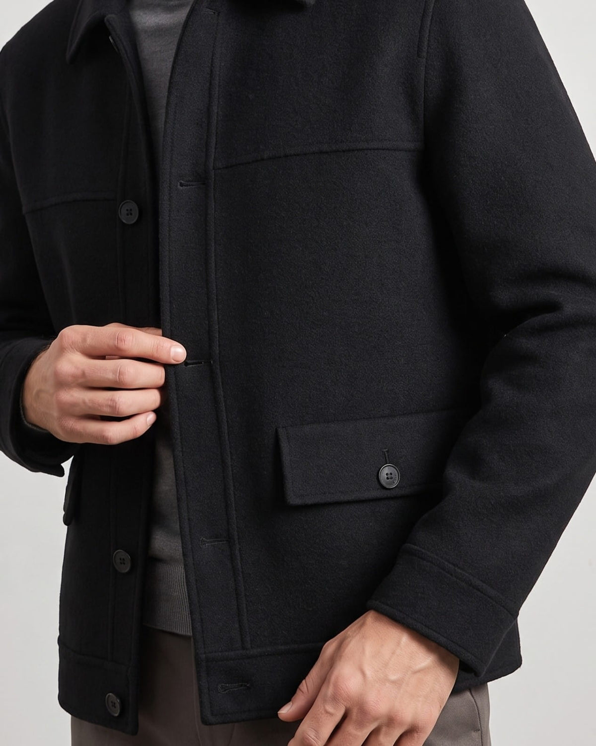 Black jacket chest detail showing the flap pocket and bound placket edge