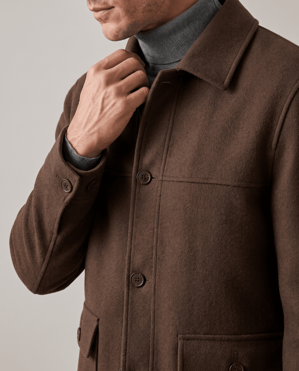 Dark brown jacket collar and placket detail with the cuff tab buttoned shut