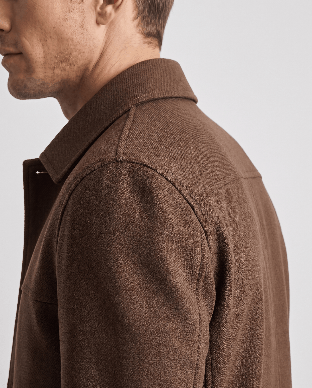 Shoulder seam close-up on a dark brown jacket showing the twill weave texture
