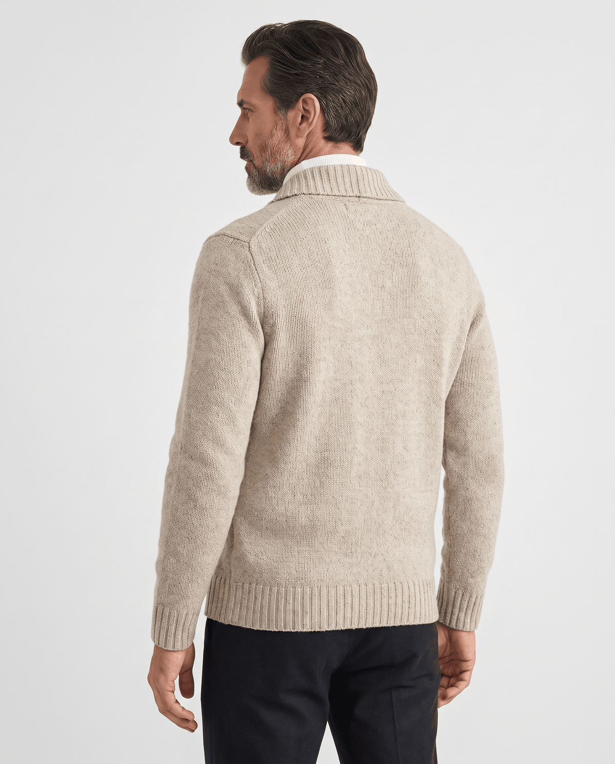 Back view of beige shawl collar cardigan worn with dark trousers