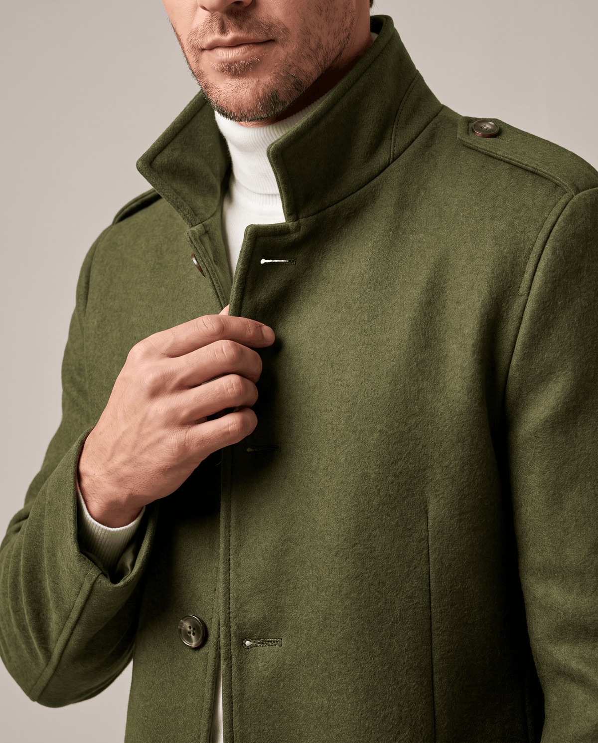 Close-up of the army green overcoat's stand collar and epaulette, with the front buttoned