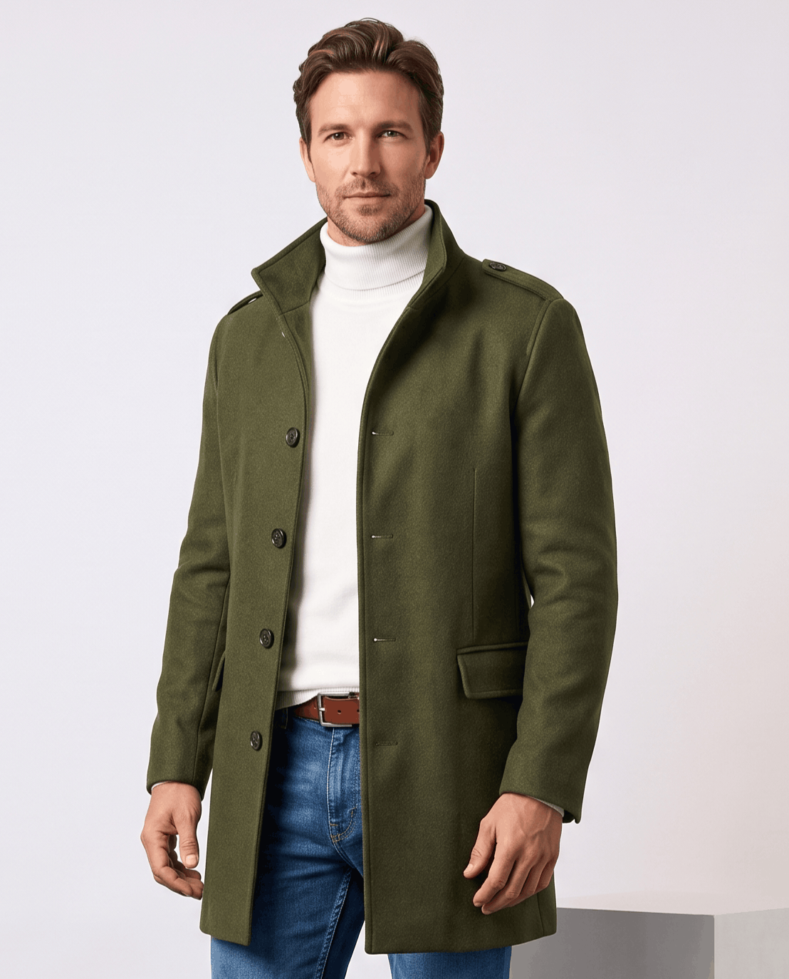 Army green overcoat with stand collar and button front, worn over a white turtleneck and jeans