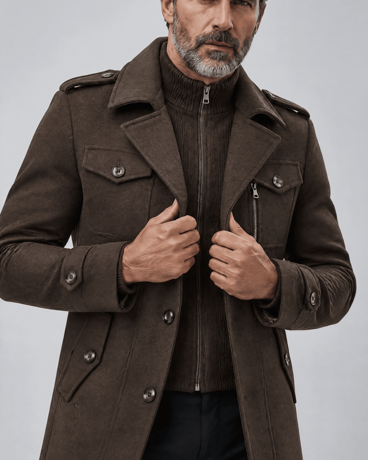 Close-up of the brown coat's button flaps, zip bib and epaulettes with both hands at the front