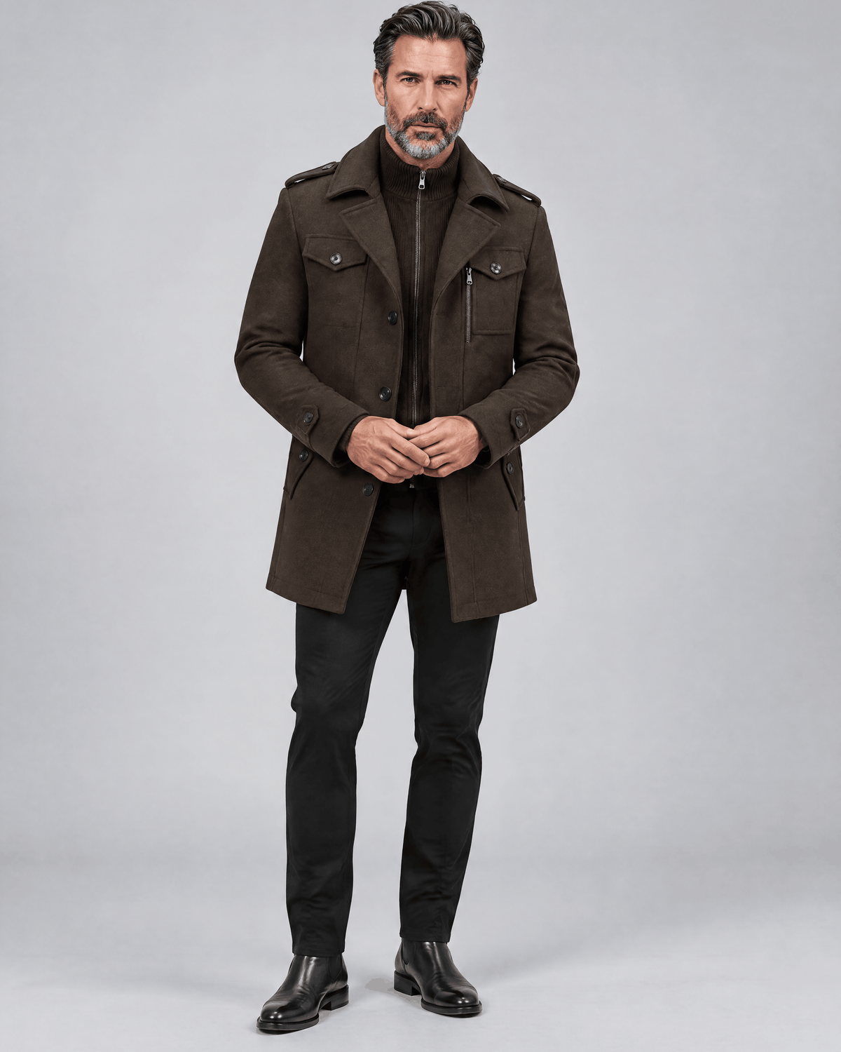 Brown thigh-length coat worn buttoned over dark trousers and black shoes, full-length front view