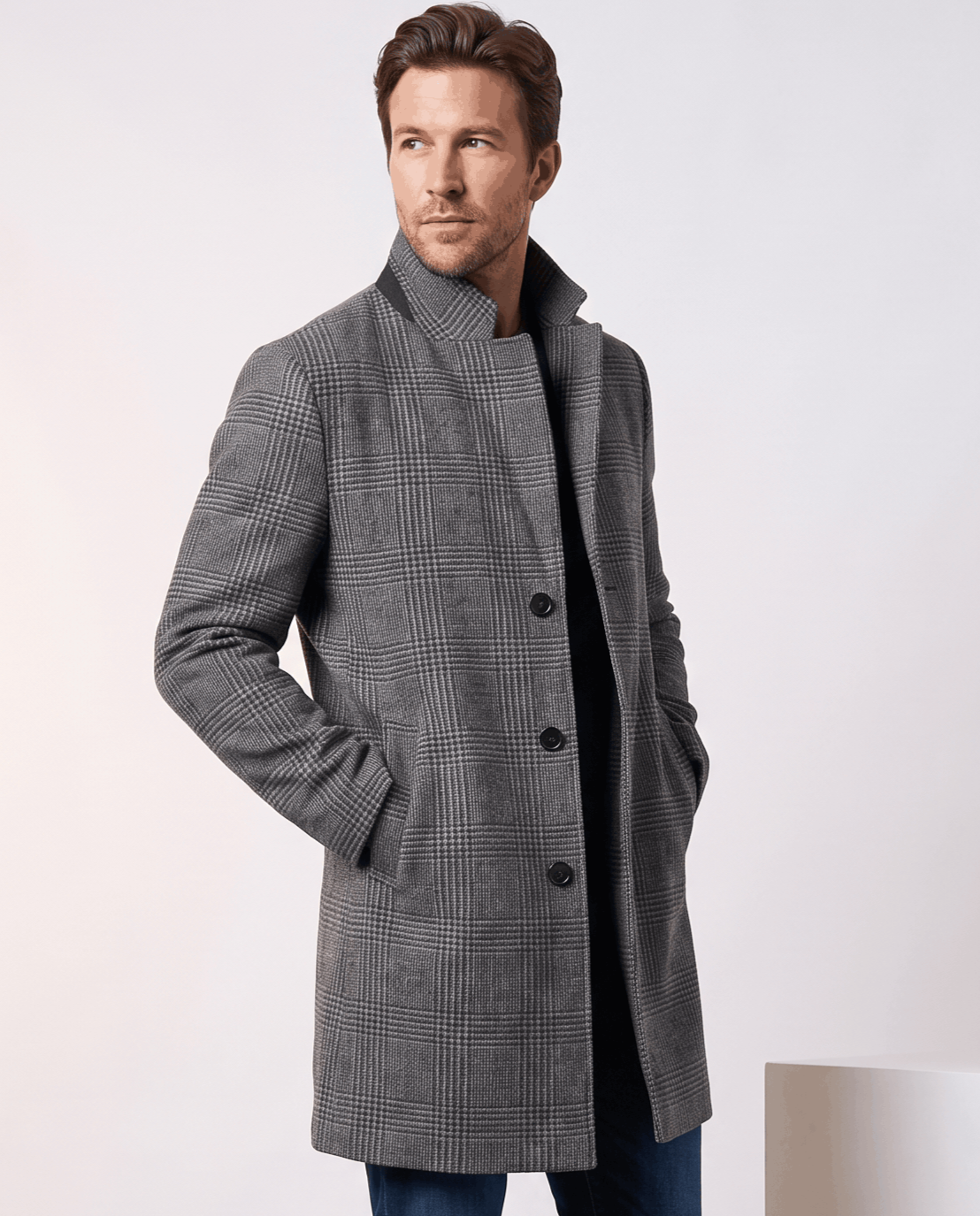 Gray check overcoat with a standing collar and button front, one hand in the pocket
