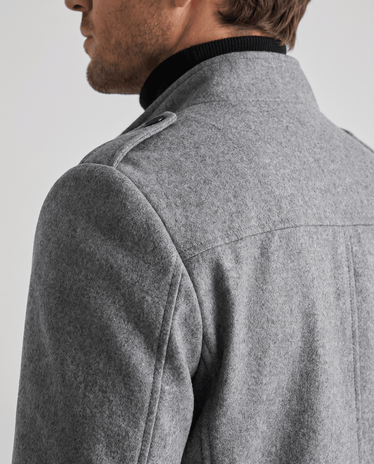 Close-up of the gray overcoat's epaulette and shoulder seam beside the stand collar