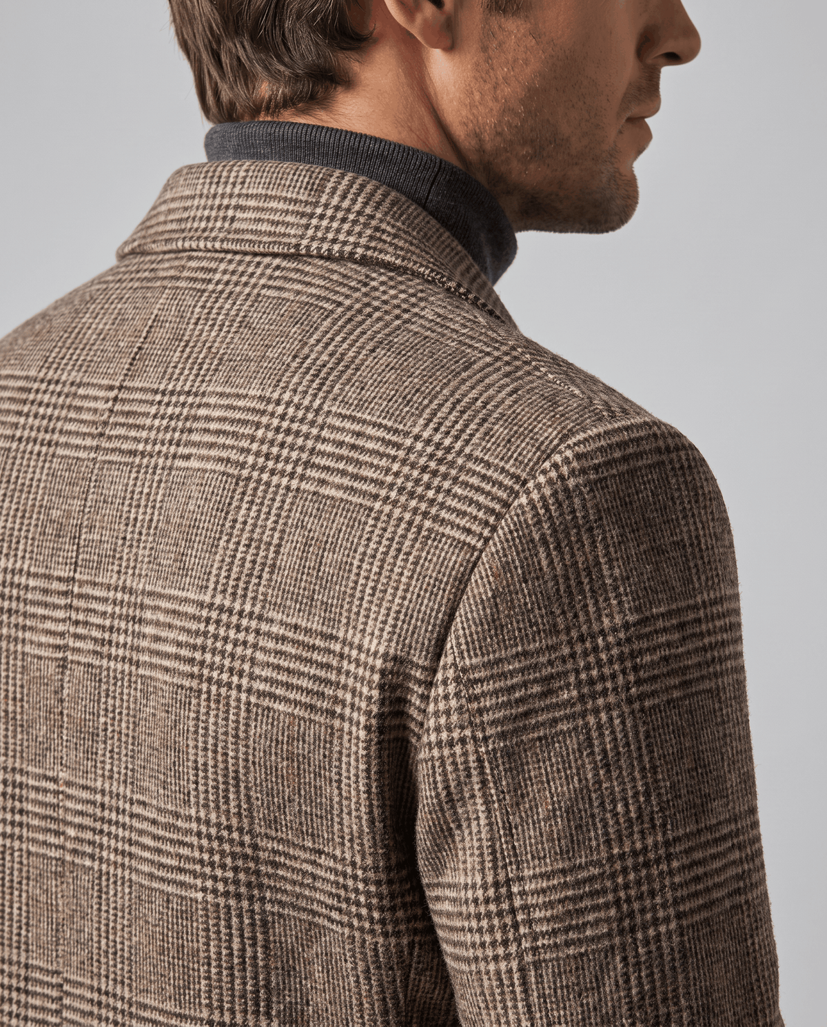 Close-up of the taupe overcoat's textured check weave across the shoulder and upper back
