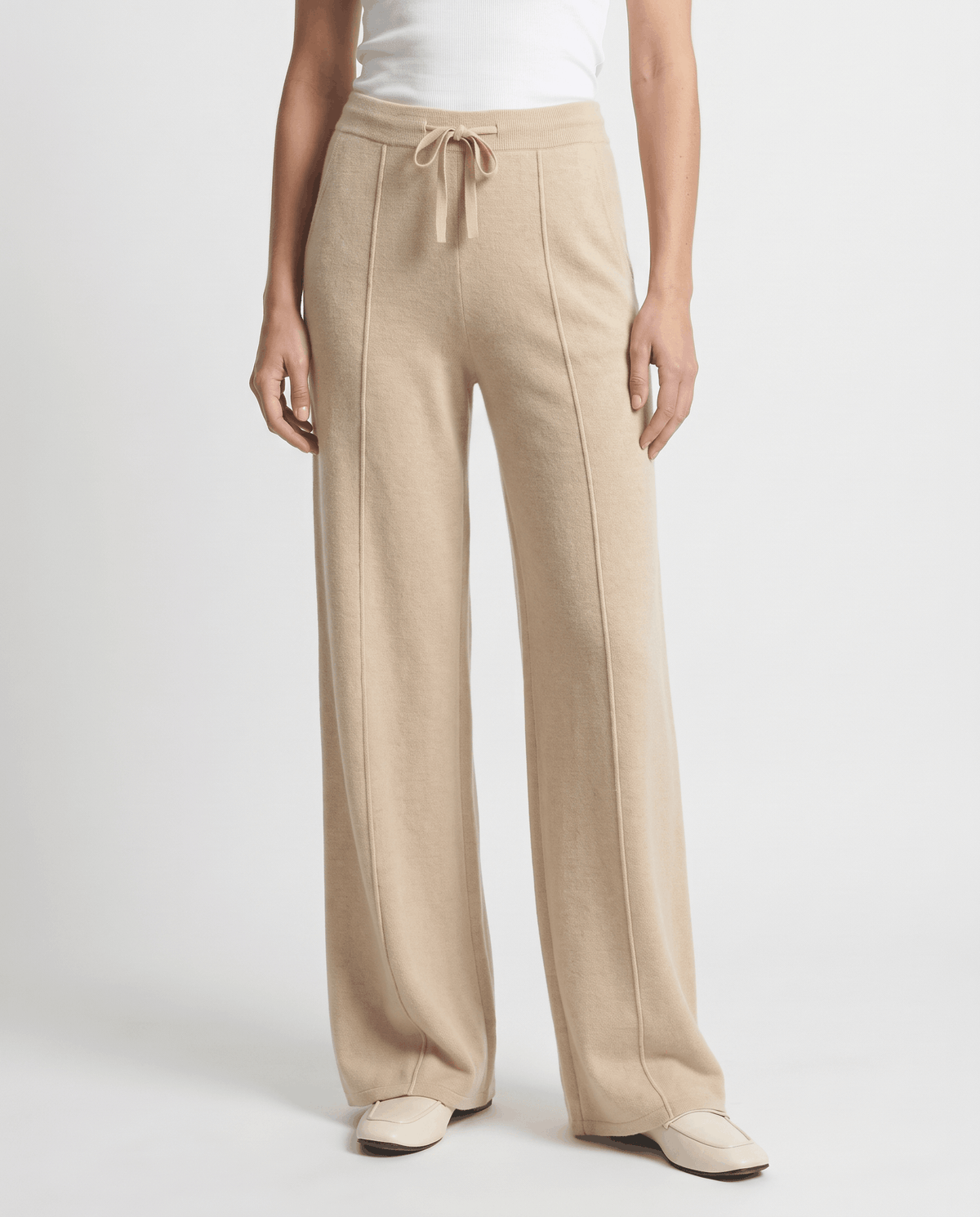 Camel knit pants in front view with pintuck seams and flats