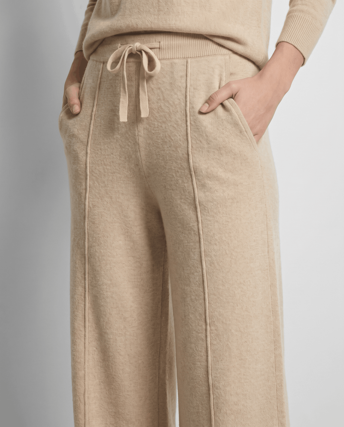 Close-up of camel drawstring waist with hands in side pockets
