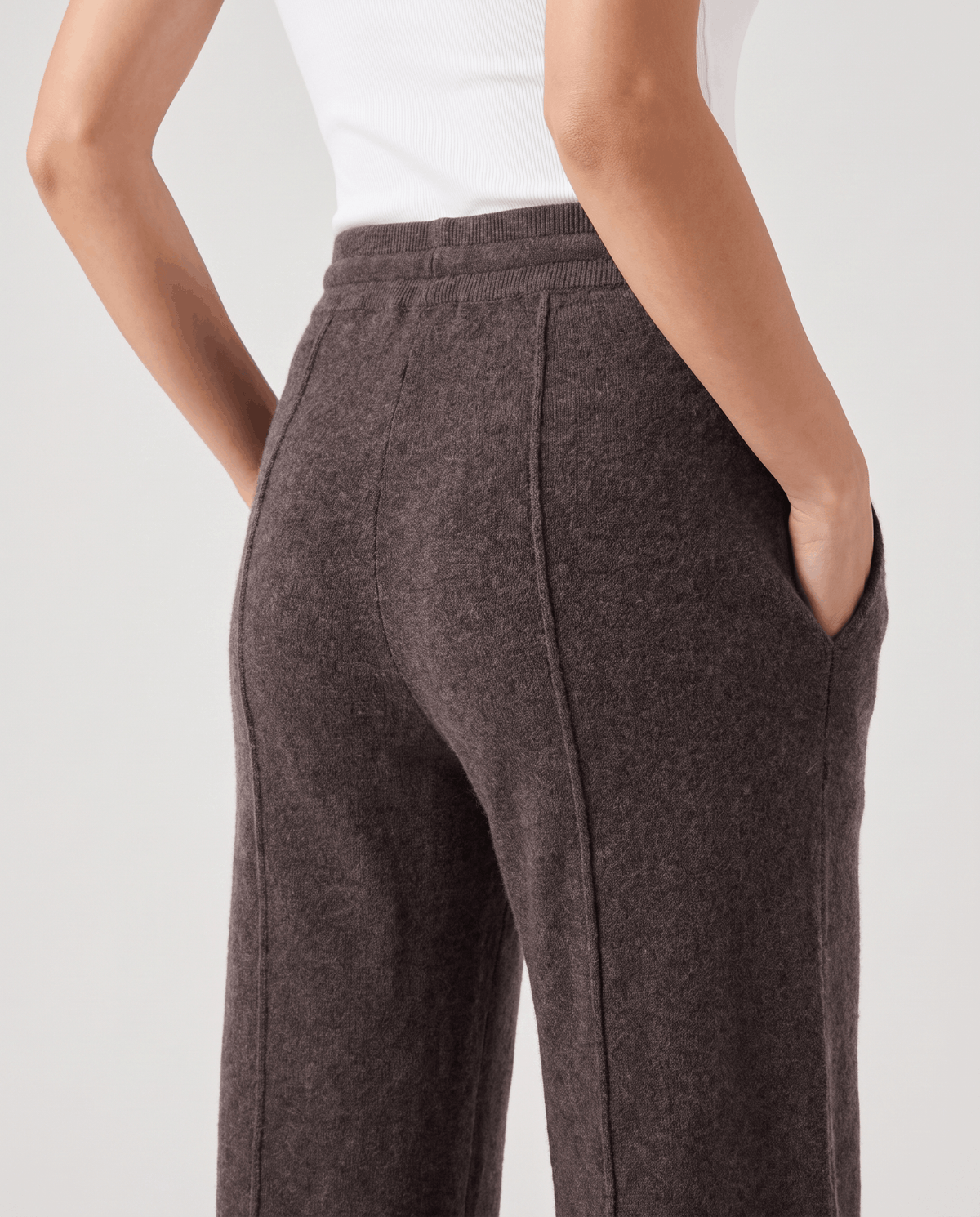Back detail of dark brown knit pants with seam and hand in pocket
