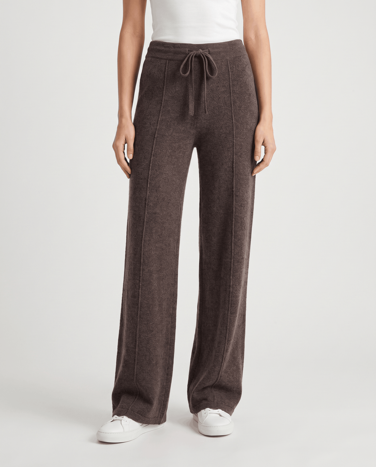 Merino wool wide-leg pants in dark brown, front view with drawstring and sneakers