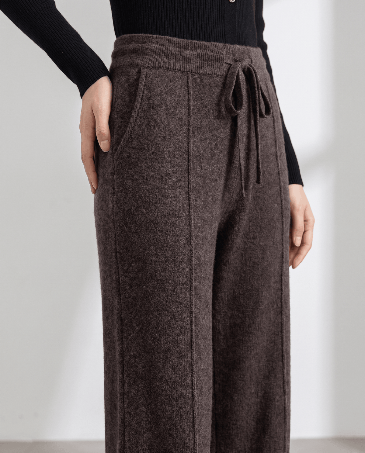 Close-up of dark brown drawstring waist with pintuck seam and side pocket