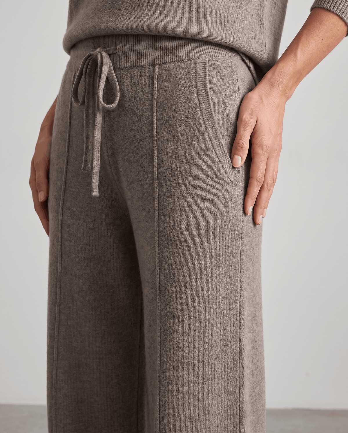 Taupe knit pants close-up with contrast drawstring and pintuck seams