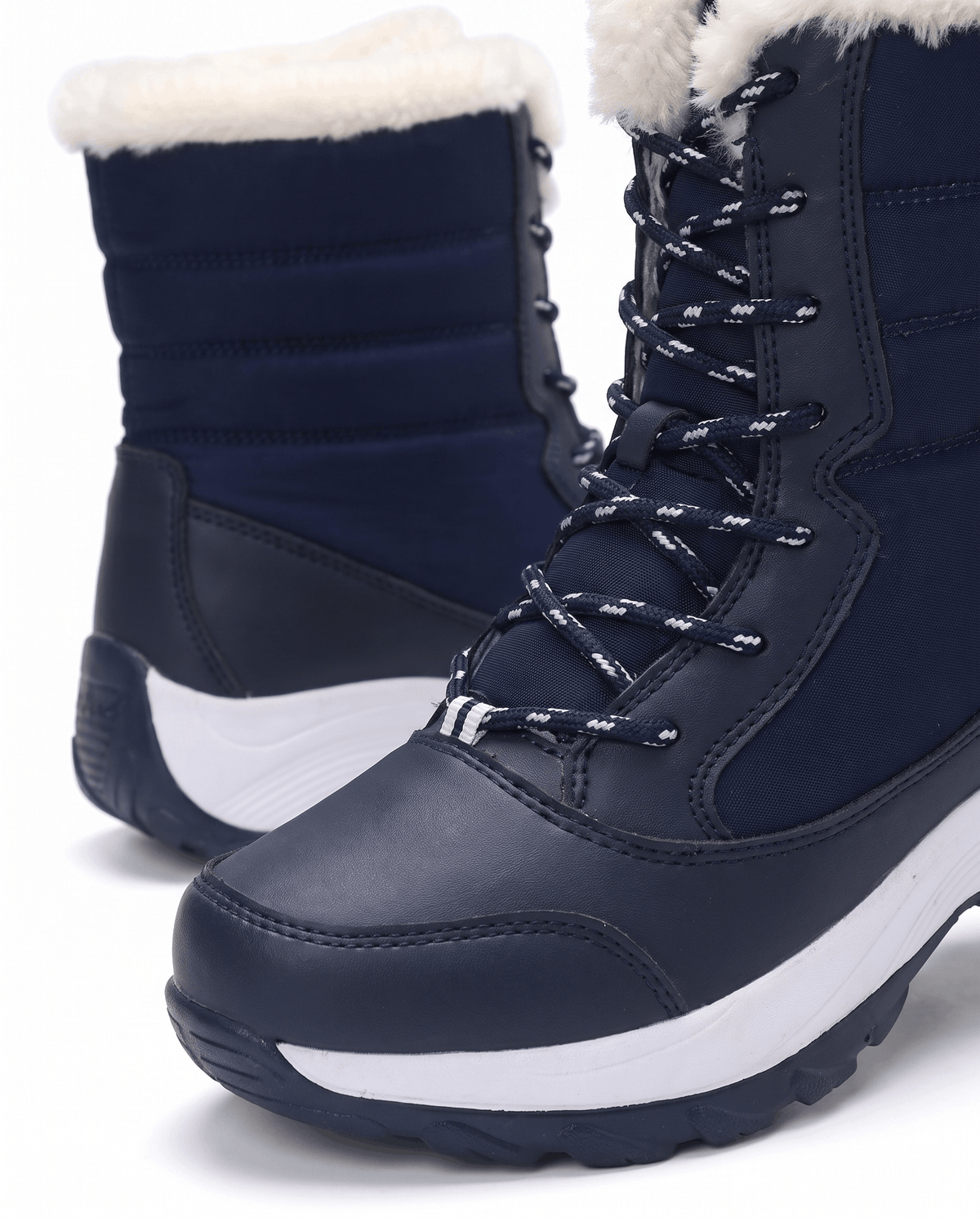 Close view of navy blue boot with white patterned laces, quilted upper and fluffy white collar