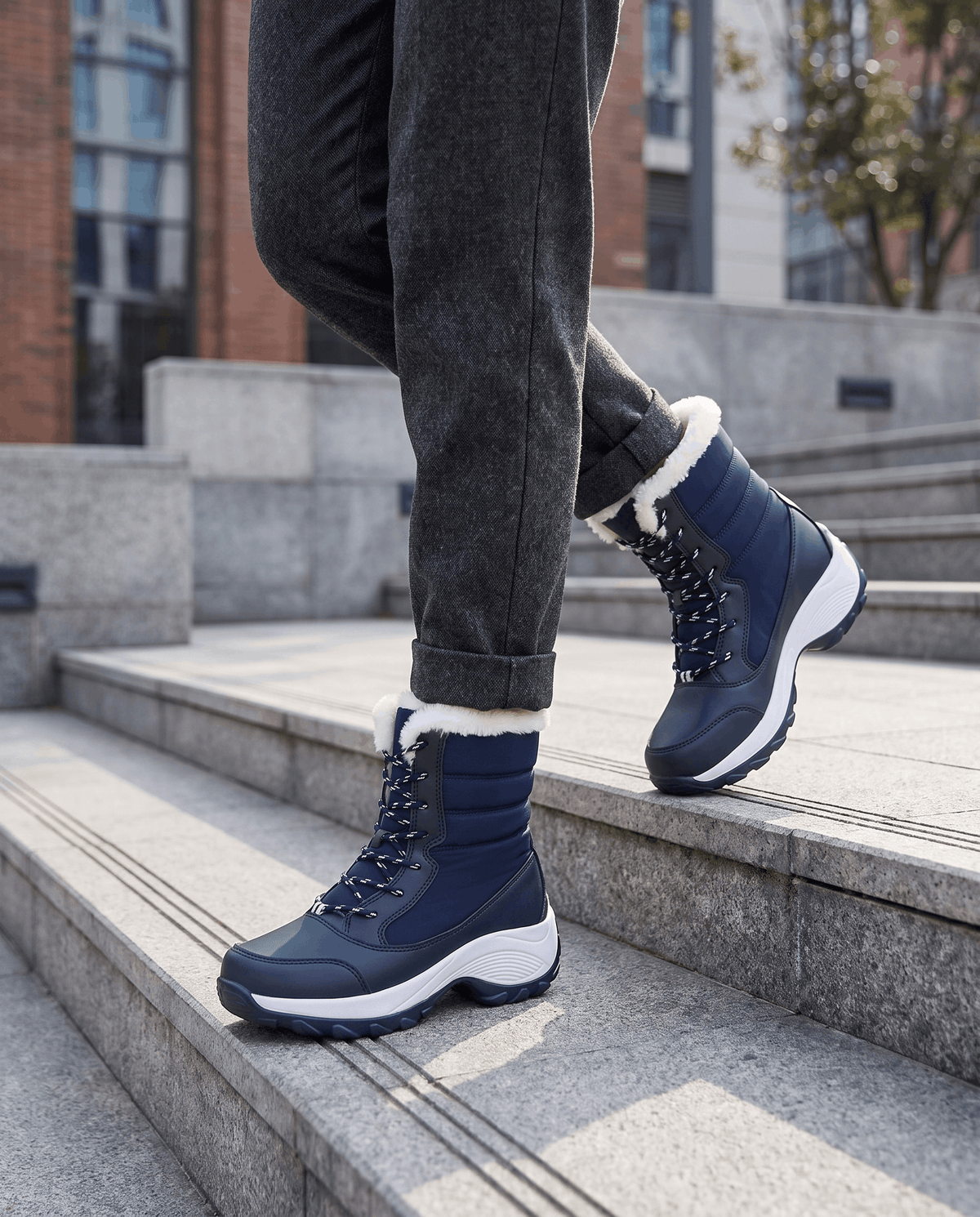 Navy blue platform boots worn with dark cuffed trousers while stepping up outdoor concrete stairs