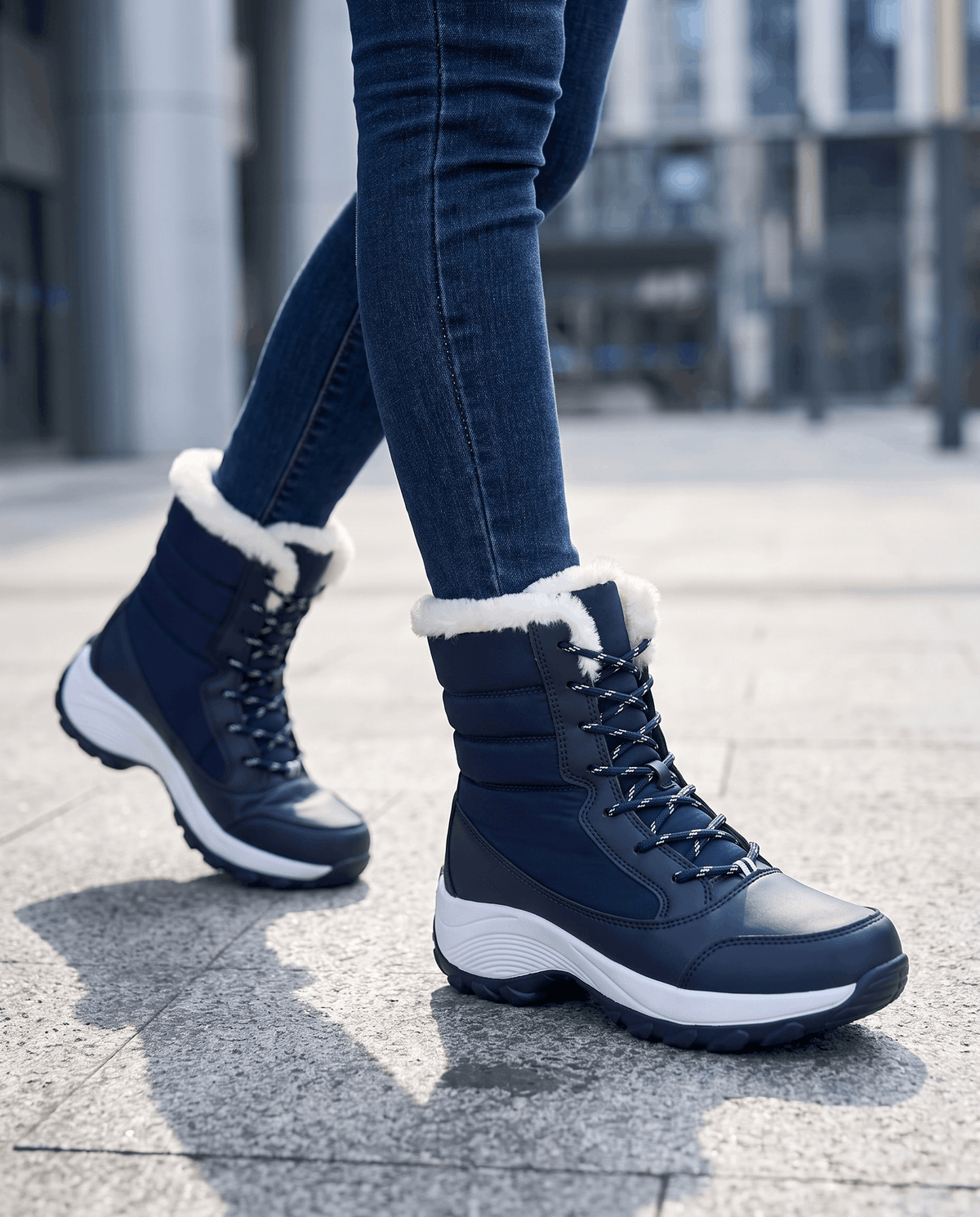 Navy blue lace-up boots with white platform soles worn with blue jeans on paved street