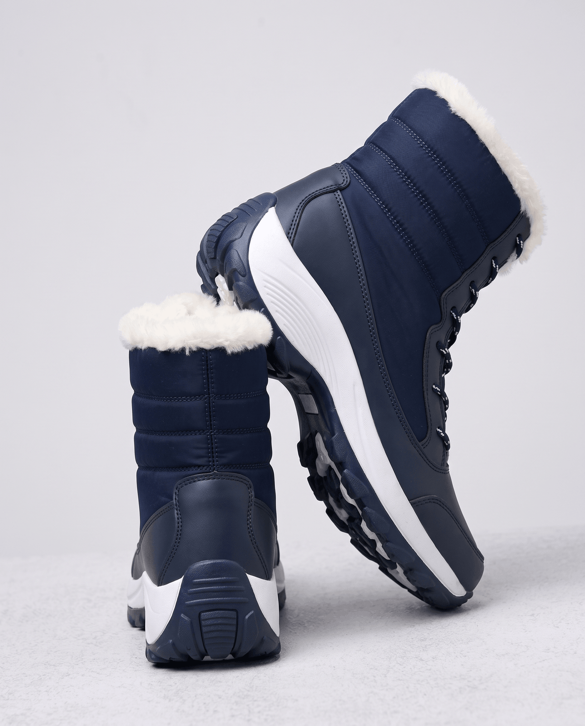 Navy blue boots angled to show quilted back, side profile and thick white platform sole