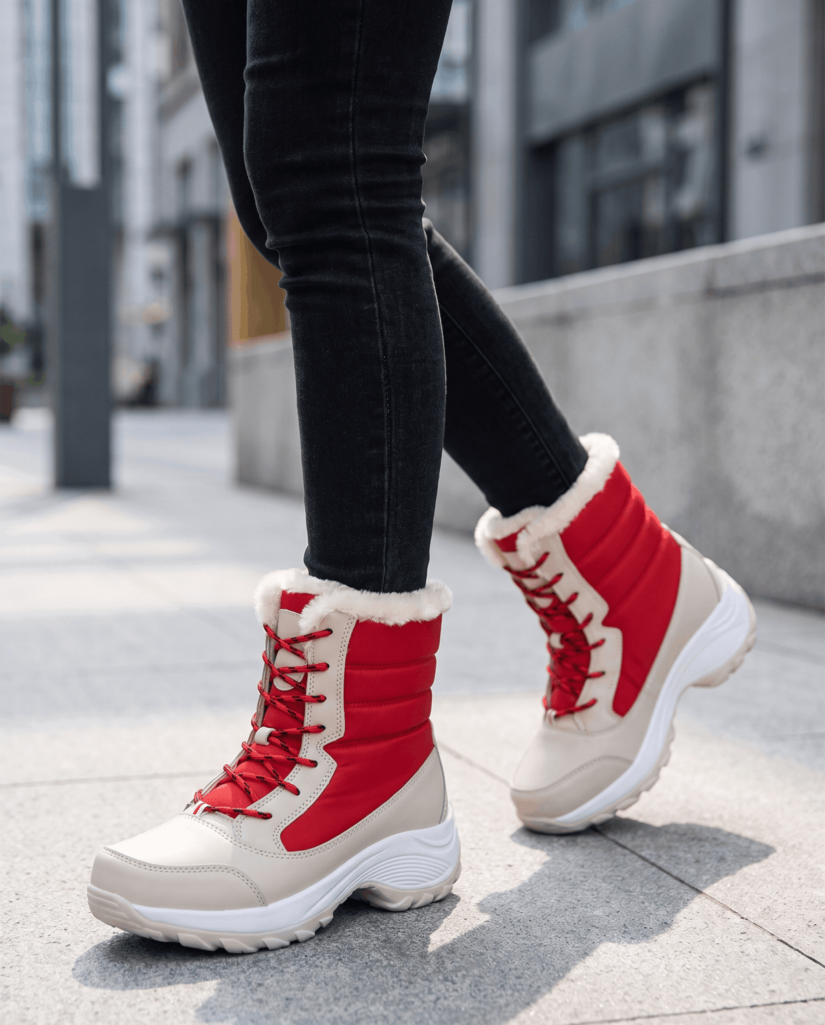 Woman wearing red and beige platform boots with black jeans, walking along a city sidewalk