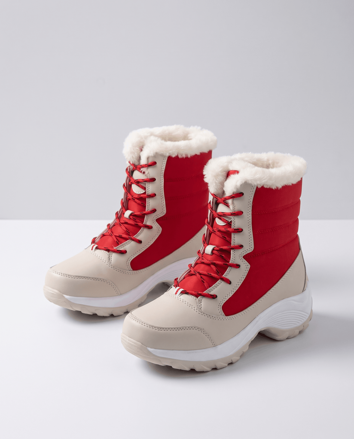 Pair of red lace-up boots with beige toes, quilted uppers and white collars on floor