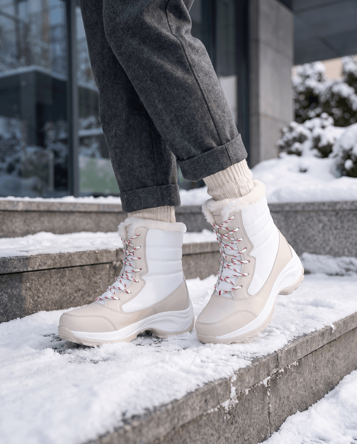 White and cream platform boots worn with dark trousers while standing on stone steps