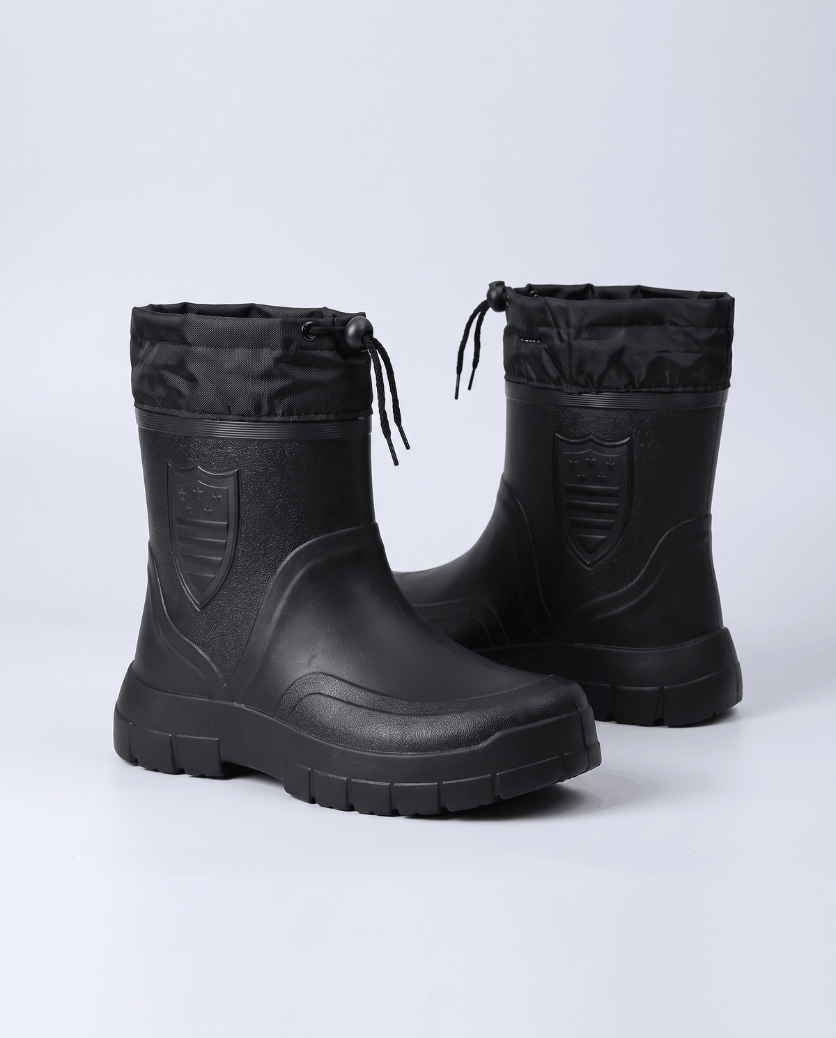 Pair of black boots angled to show cord collars and chunky treaded soles