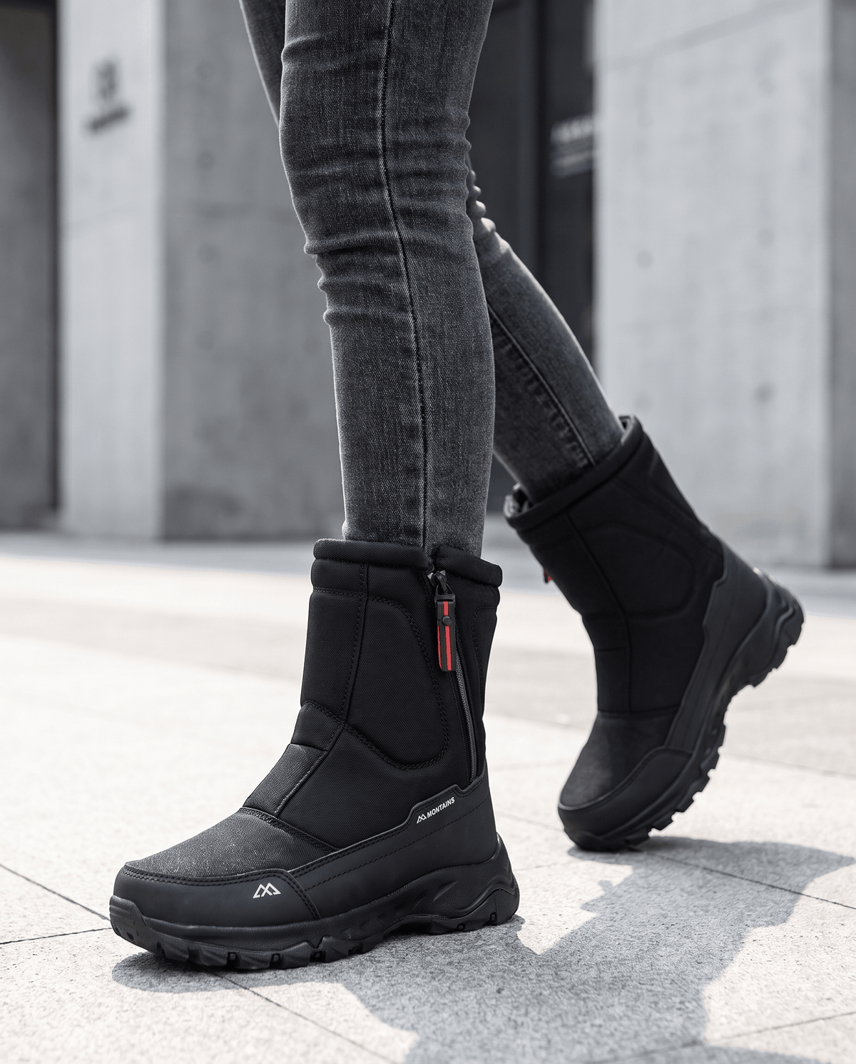 Black snow boots worn with grey leggings while standing on a city sidewalk