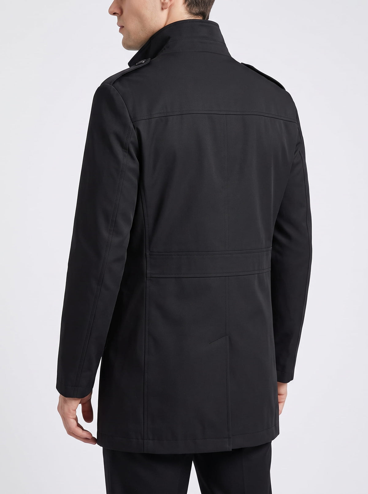 Back view of black trench coat with epaulets and center vent, worn with black trousers