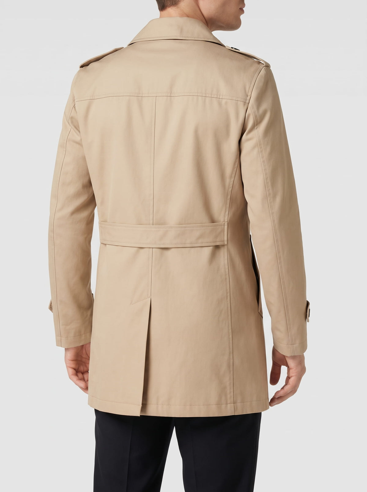 Back view of khaki trench coat with epaulets and center vent, worn with black trousers