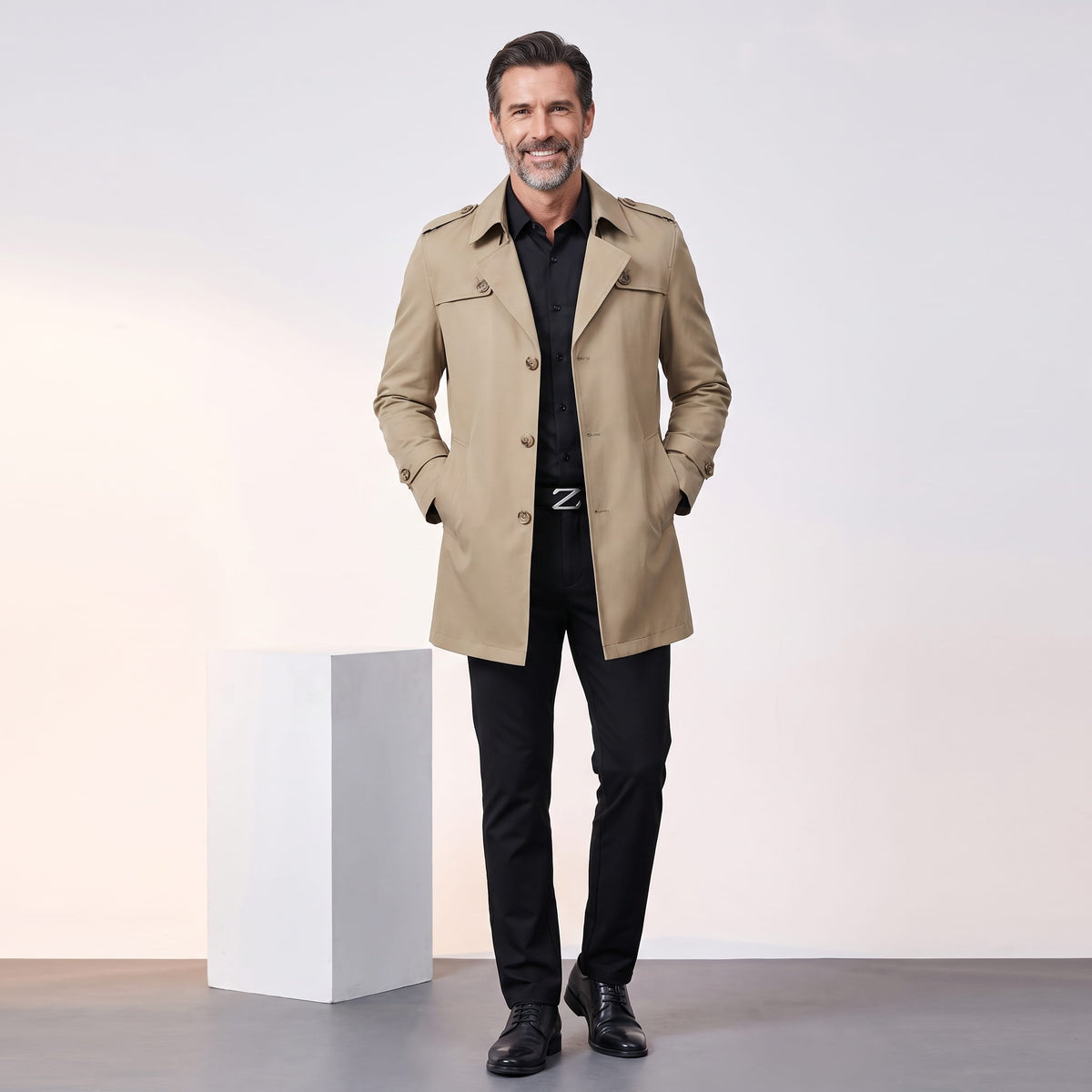 Full-length khaki trench coat styled with black shirt and trousers, hands in pockets