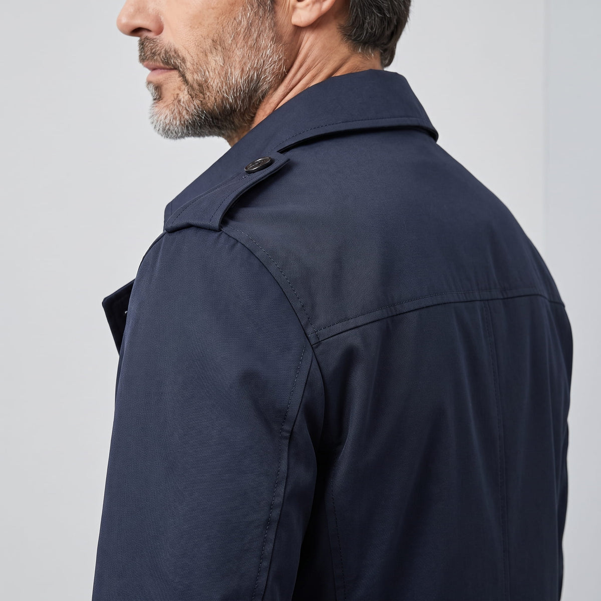 Side-back view of navy blue trench coat showing shoulder epaulet and collar