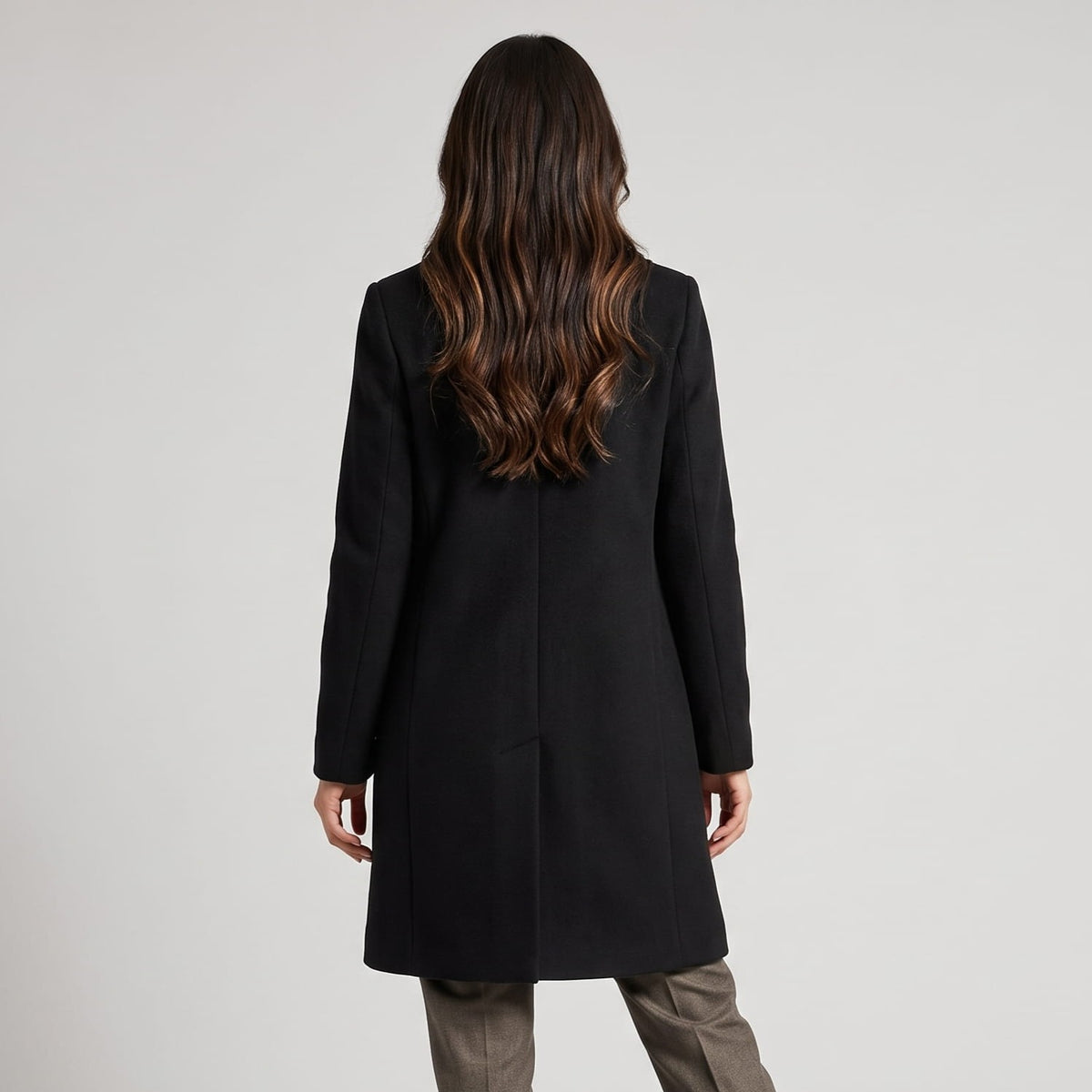 Back view of black coat showing its straight tailored line and long sleeves