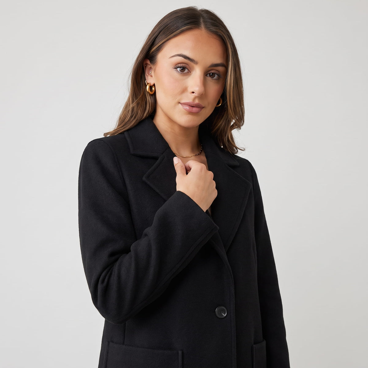 Close-up of black coat front with notched lapel and single button closure