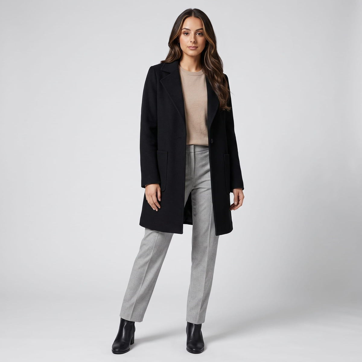Full-length view of black coat styled with gray trousers and black ankle boots