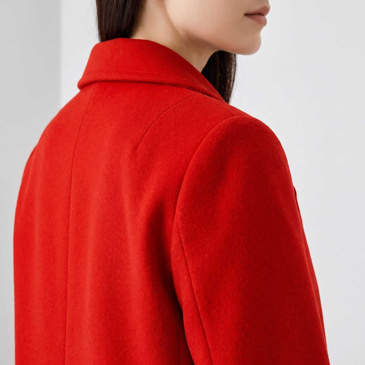 Detail of cherry red coat collar and shoulder seam from behind