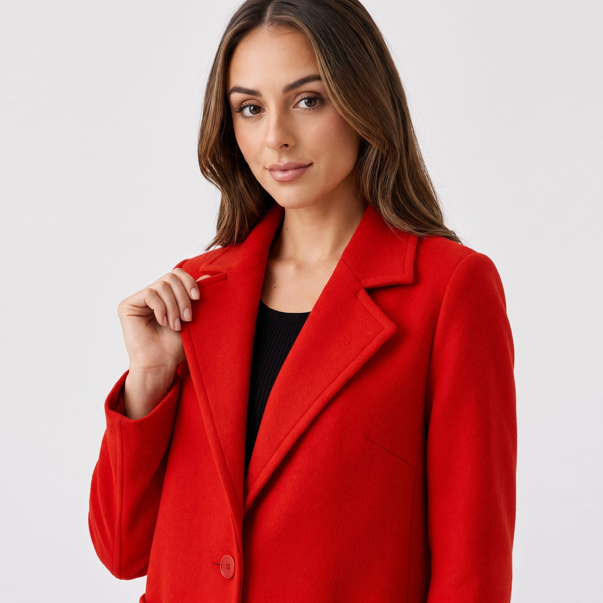 Close-up of model holding the notched lapel of a cherry red coat