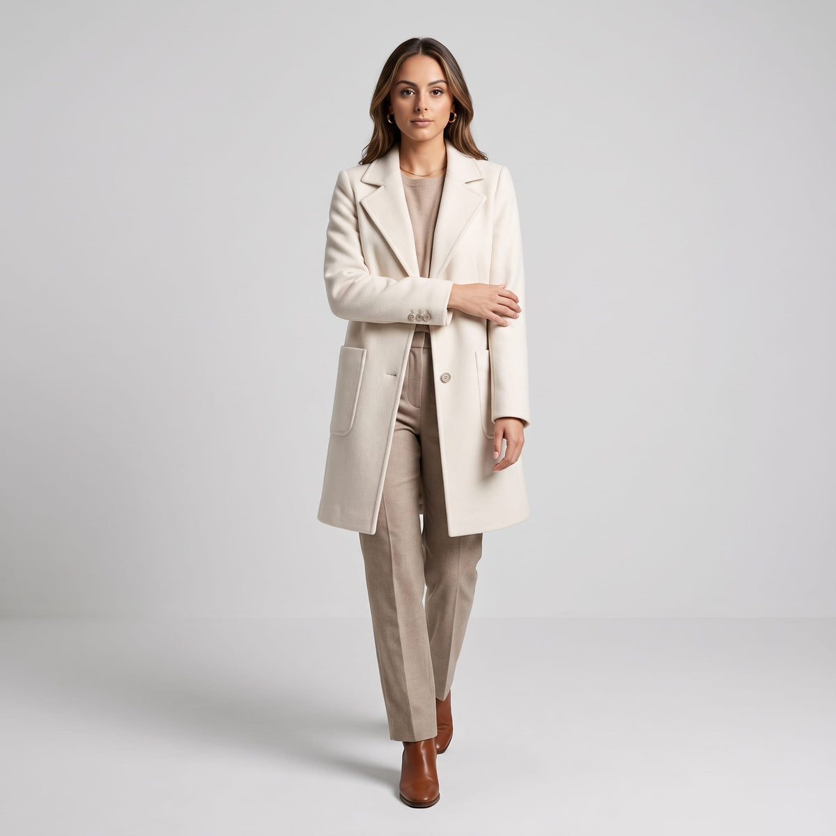 Model walking in cream coat paired with light beige trousers