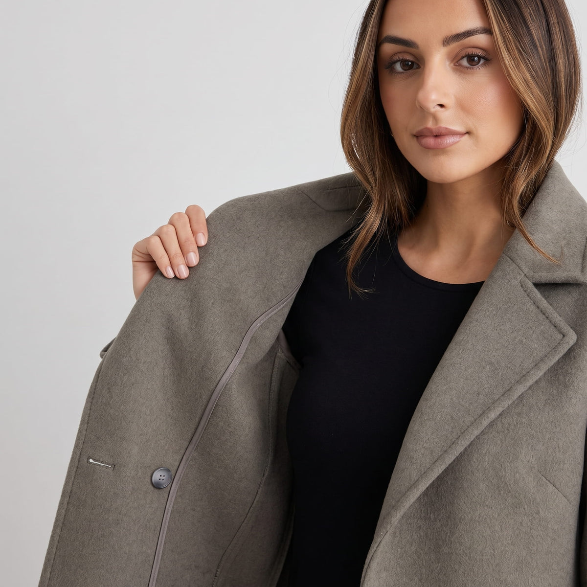 Model opening olive green coat to show the front button and lapel