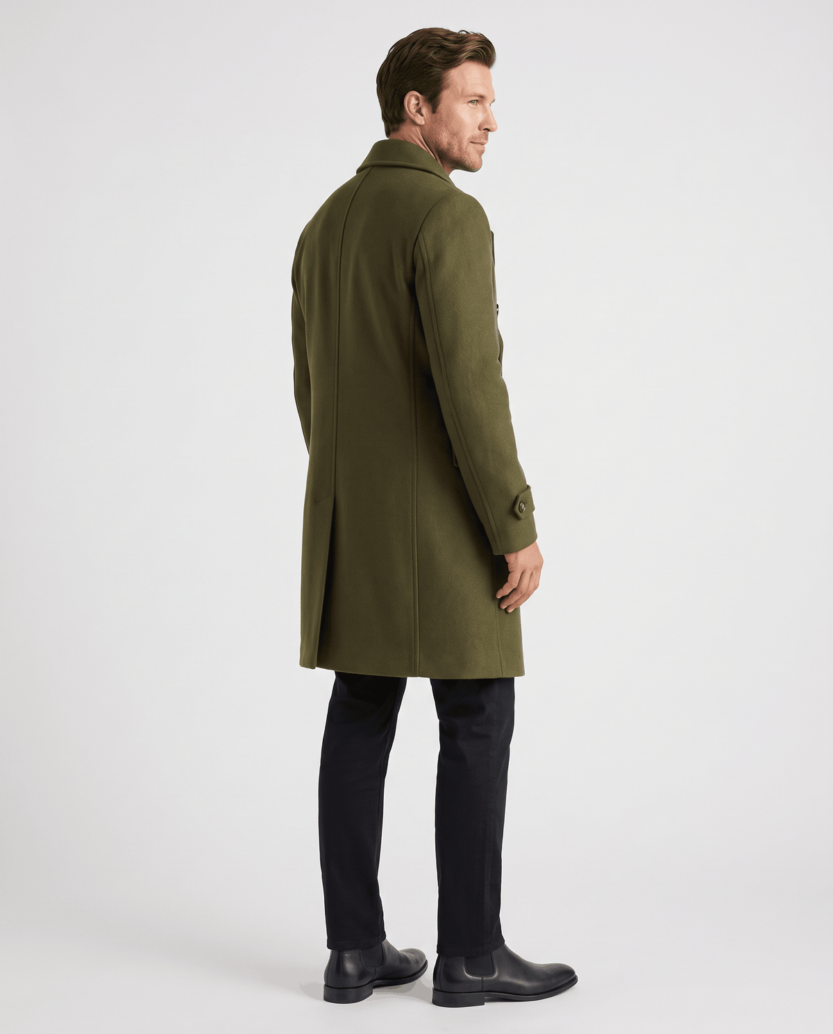 Side view of a long olive green wool coat with dark trousers and black shoes