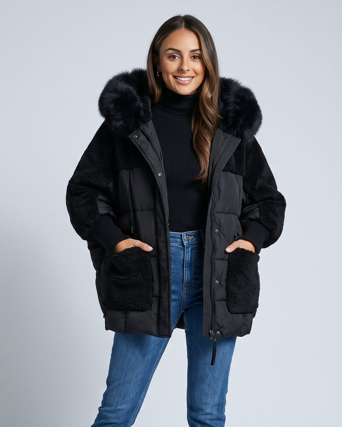 Woman in black oversized hooded parka with patch pockets and blue jeans